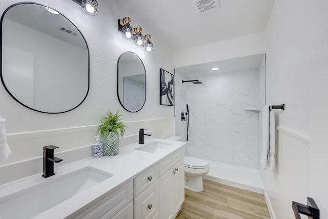 bathroom with tiled shower, toilet, vanity, and hardwood / wood-style flooring