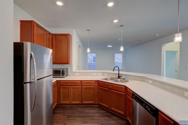 kitchen featuring sink, dark wood-type flooring, kitchen peninsula, decorative light fixtures, and appliances with stainless steel finishes