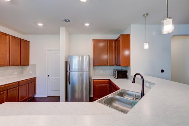 kitchen with dark wood-type flooring, sink, stainless steel fridge, tasteful backsplash, and decorative light fixtures