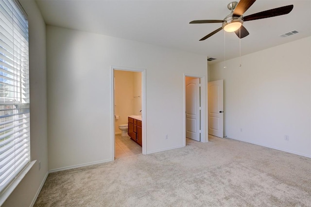 unfurnished bedroom featuring light carpet, ensuite bath, and ceiling fan