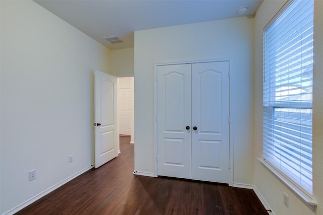 unfurnished bedroom with a closet and dark wood-type flooring