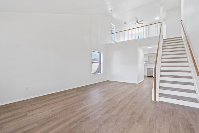 unfurnished living room with ceiling fan, high vaulted ceiling, and hardwood / wood-style flooring