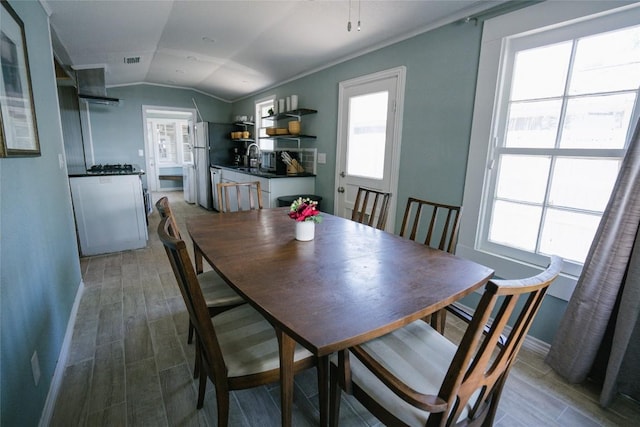 dining area with a healthy amount of sunlight, vaulted ceiling, and wood-type flooring