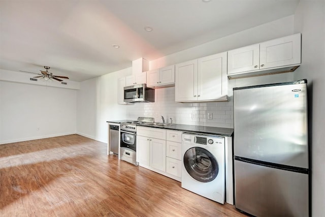 kitchen with appliances with stainless steel finishes, ceiling fan, light hardwood / wood-style flooring, washer / dryer, and white cabinetry