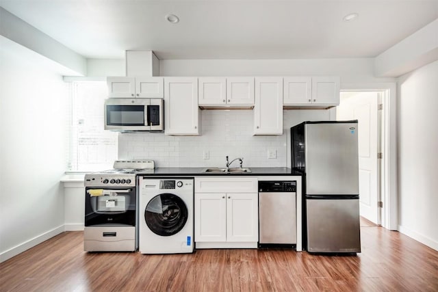 kitchen featuring white cabinetry, sink, stainless steel appliances, washer / dryer, and light wood-type flooring