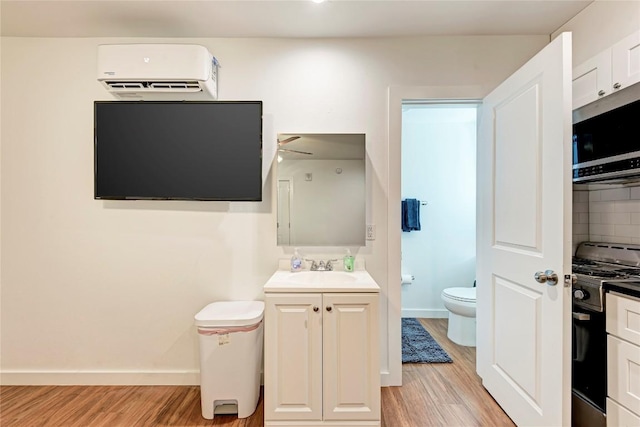 bathroom featuring backsplash, vanity, an AC wall unit, hardwood / wood-style floors, and toilet