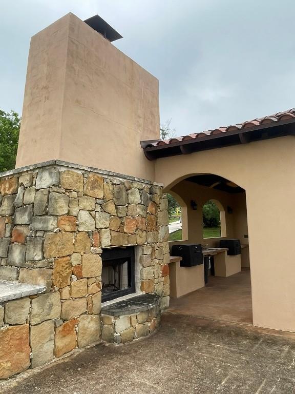 view of patio featuring an outdoor stone fireplace and an outdoor kitchen