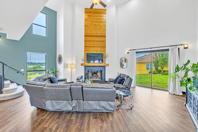 living room with a wealth of natural light, a fireplace, a towering ceiling, and wood-type flooring