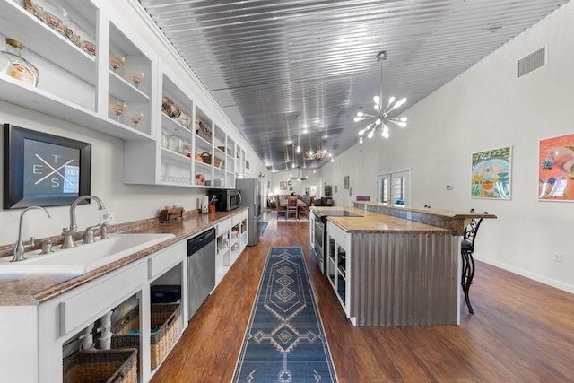 kitchen with white cabinetry, sink, dark hardwood / wood-style floors, a kitchen island, and appliances with stainless steel finishes