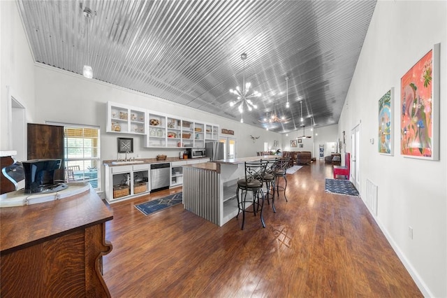 kitchen featuring a kitchen breakfast bar, dark hardwood / wood-style floors, stainless steel fridge, a towering ceiling, and a kitchen island