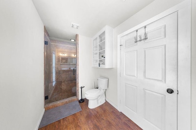 bathroom featuring hardwood / wood-style floors, toilet, and a shower with door