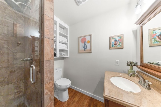 bathroom with hardwood / wood-style floors, vanity, toilet, and walk in shower