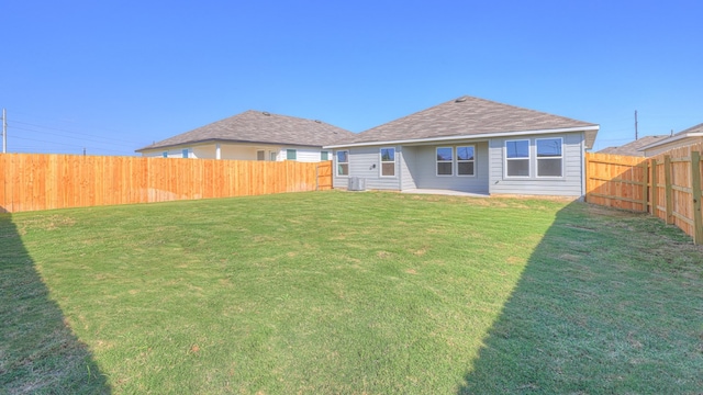 rear view of property with central AC unit and a yard