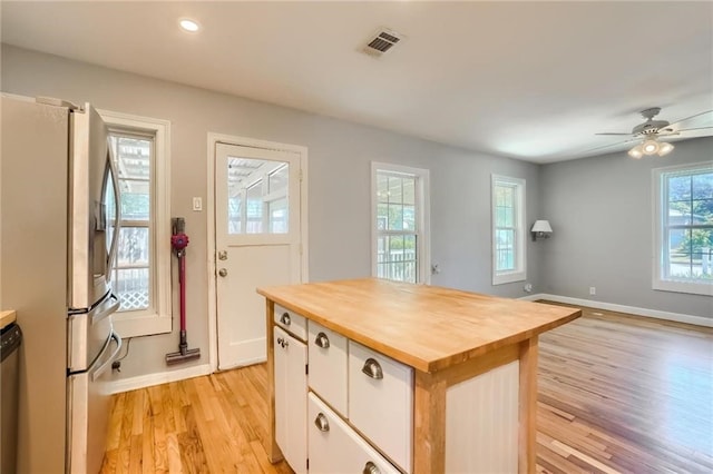 kitchen with white cabinets, light hardwood / wood-style flooring, appliances with stainless steel finishes, a kitchen island, and butcher block counters