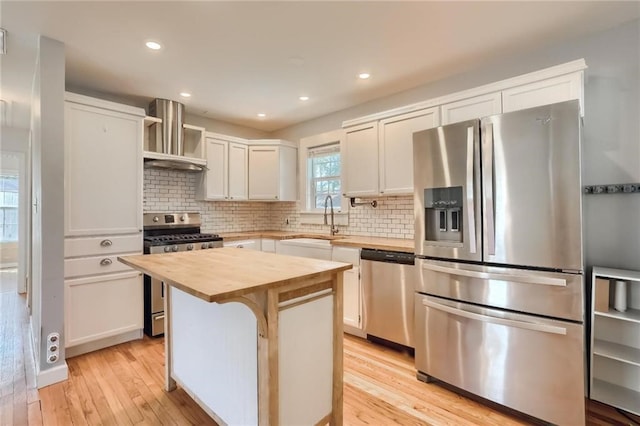 kitchen featuring white cabinetry, sink, appliances with stainless steel finishes, a kitchen island, and light wood-type flooring