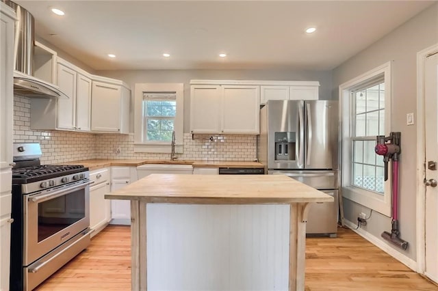 kitchen with white cabinets, plenty of natural light, a kitchen island, and stainless steel appliances