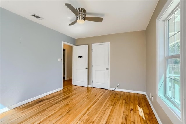 unfurnished bedroom featuring multiple windows, ceiling fan, and light wood-type flooring