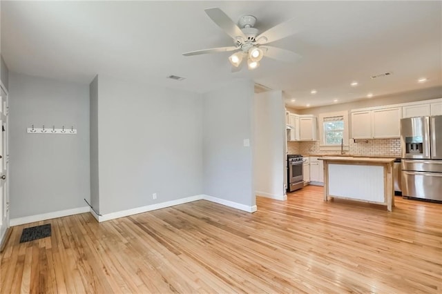 kitchen featuring white cabinets, light hardwood / wood-style flooring, ceiling fan, appliances with stainless steel finishes, and a kitchen island