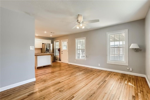 unfurnished living room featuring ceiling fan and light hardwood / wood-style floors