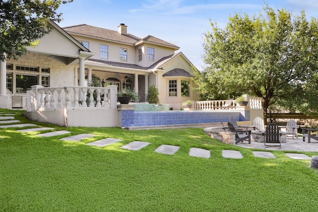 back of property with a fire pit, a yard, and a patio