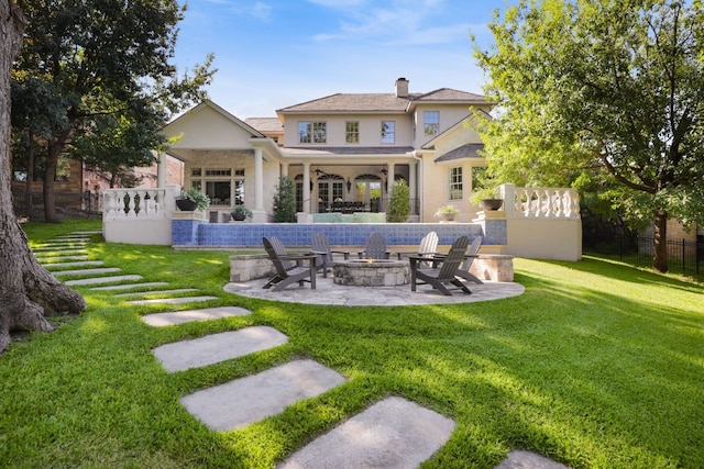 rear view of house featuring a yard, a fire pit, and a patio area