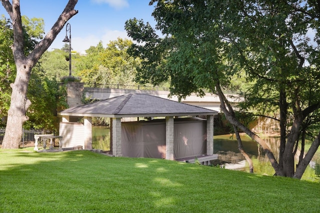 exterior space featuring a garage, a water view, an outbuilding, and a front yard