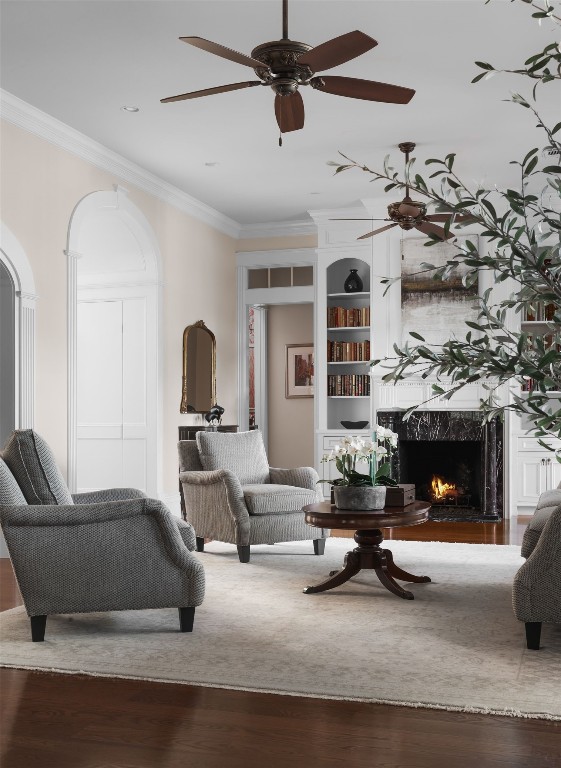 living room with ceiling fan, dark hardwood / wood-style flooring, crown molding, and a high end fireplace