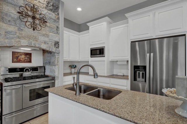 kitchen with sink, light tile patterned floors, light stone counters, white cabinetry, and stainless steel appliances