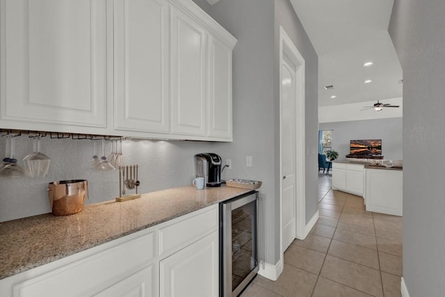 bar with light stone countertops, white cabinetry, beverage cooler, decorative backsplash, and light tile patterned flooring