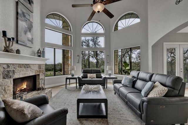 living room with a fireplace, a high ceiling, ceiling fan, and a healthy amount of sunlight