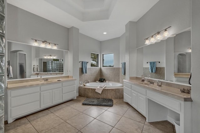 bathroom with tile patterned floors, tiled bath, and vanity