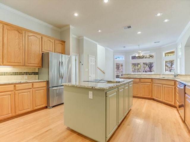 kitchen with ceiling fan, sink, stainless steel appliances, a kitchen island, and light wood-type flooring