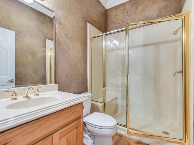 bathroom featuring hardwood / wood-style floors, toilet, vanity, a shower with shower door, and ornamental molding