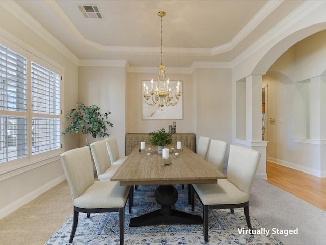 dining space featuring a tray ceiling, a notable chandelier, and ornamental molding