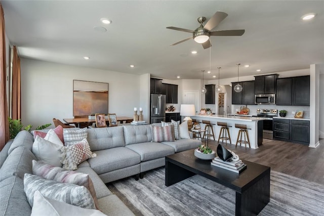 living room with ceiling fan, sink, and dark hardwood / wood-style floors