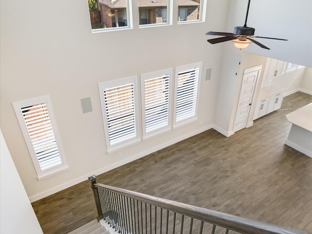 living room with ceiling fan, a towering ceiling, and dark wood-type flooring