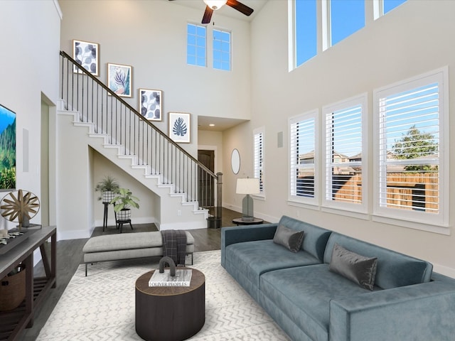 living room featuring hardwood / wood-style floors, ceiling fan, a towering ceiling, and a wealth of natural light