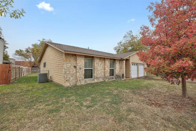 back of house with a lawn, central AC, and a garage