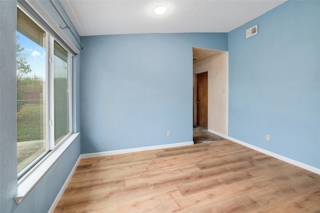 spare room featuring vaulted ceiling and light wood-type flooring