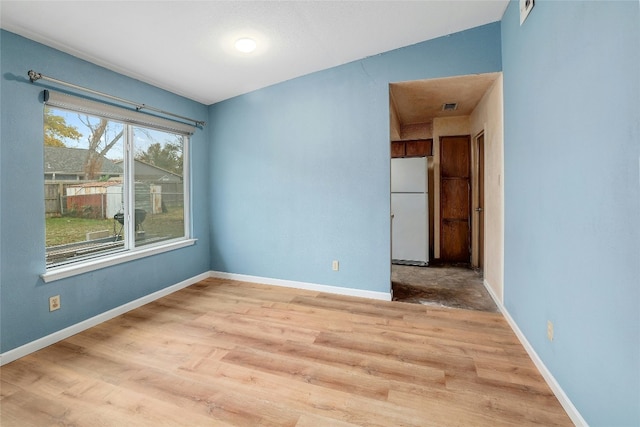 unfurnished room with light wood-type flooring and vaulted ceiling