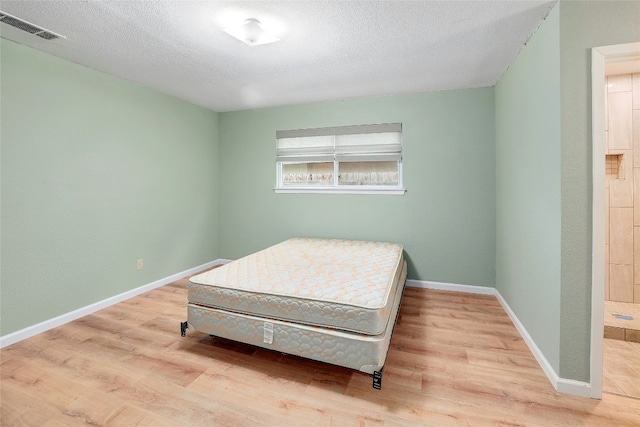 bedroom with a textured ceiling and light hardwood / wood-style flooring