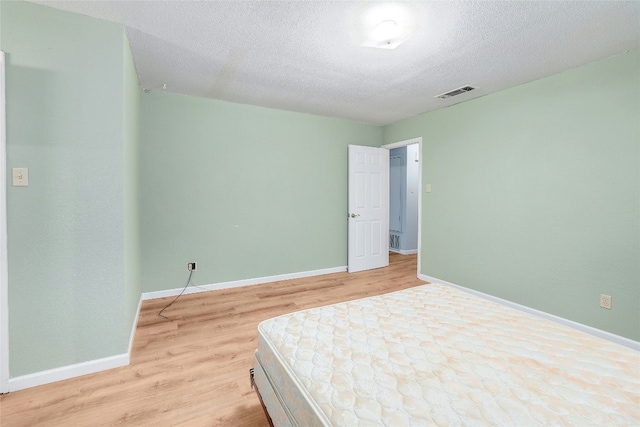 bedroom featuring light wood-type flooring and a textured ceiling