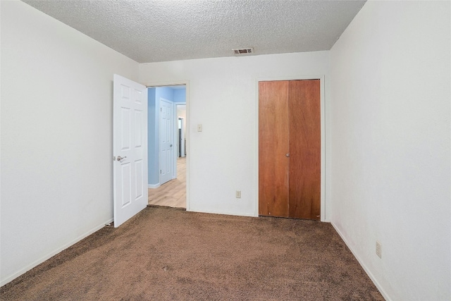 unfurnished bedroom with carpet flooring, a textured ceiling, and a closet