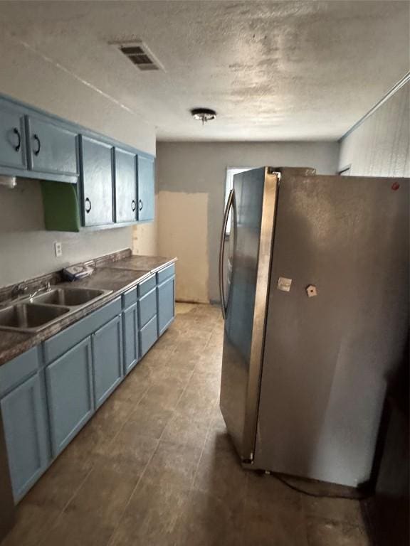 kitchen featuring blue cabinetry, stainless steel refrigerator, and sink