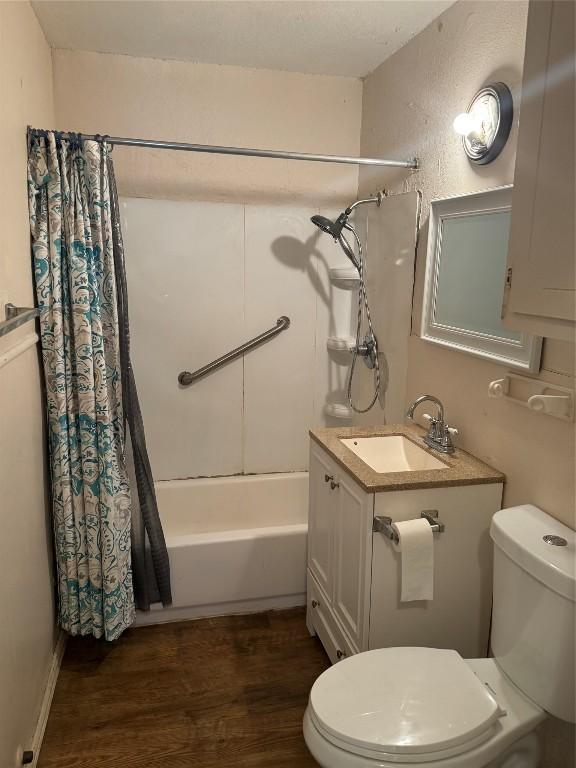 full bathroom featuring hardwood / wood-style floors, vanity, shower / tub combo, and toilet