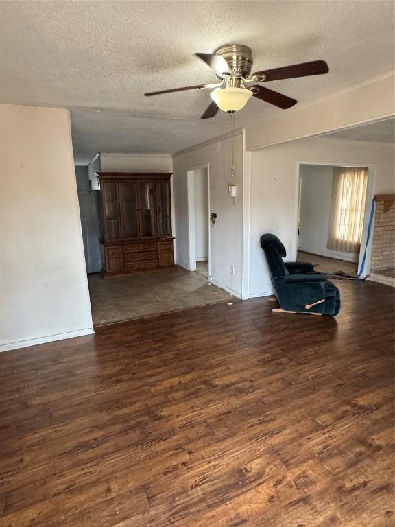 unfurnished living room with dark hardwood / wood-style floors, ceiling fan, and a textured ceiling