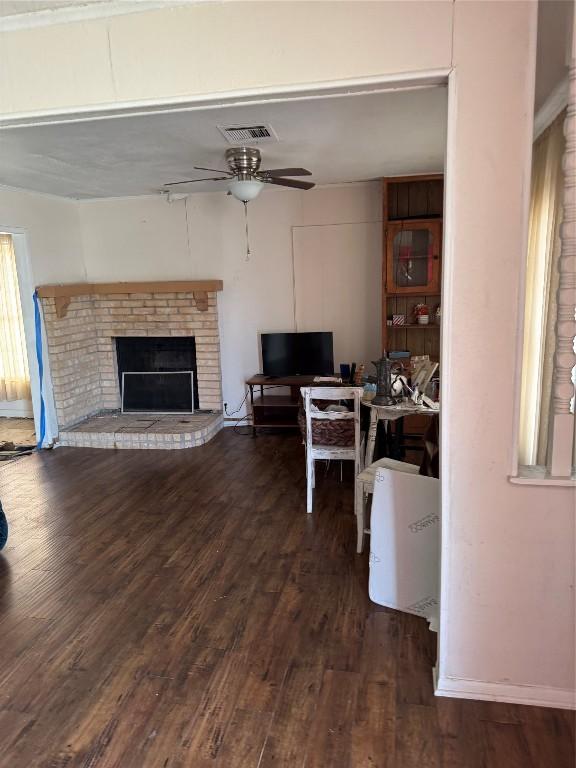 living room featuring ceiling fan, dark hardwood / wood-style flooring, and a brick fireplace