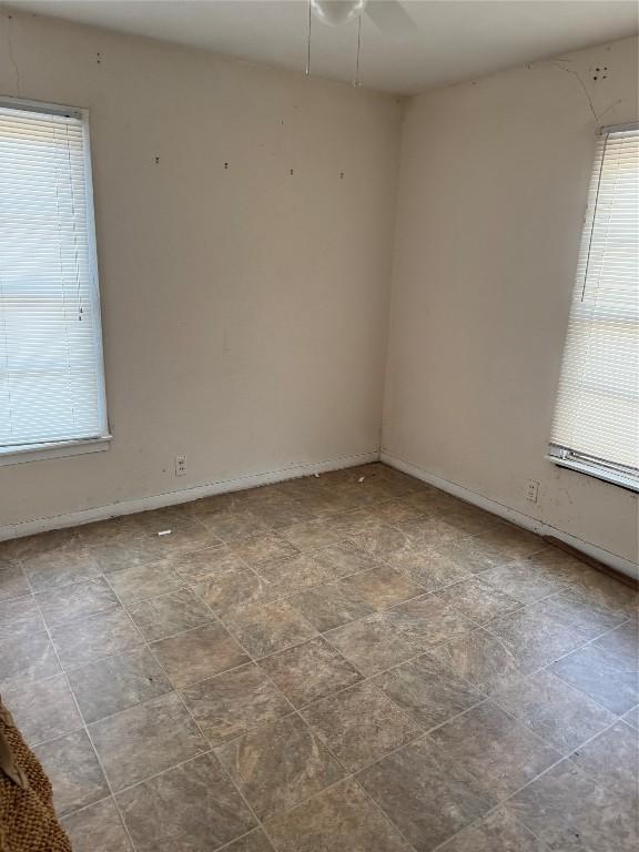 unfurnished room featuring ceiling fan and plenty of natural light