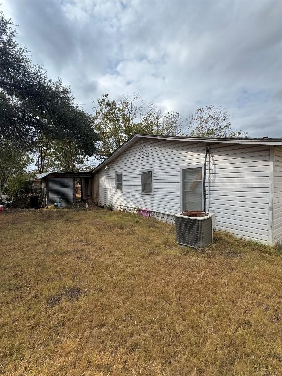 view of side of property featuring a lawn and central air condition unit