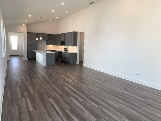 kitchen with dark wood-type flooring, open floor plan, an island with sink, appliances with stainless steel finishes, and a sink